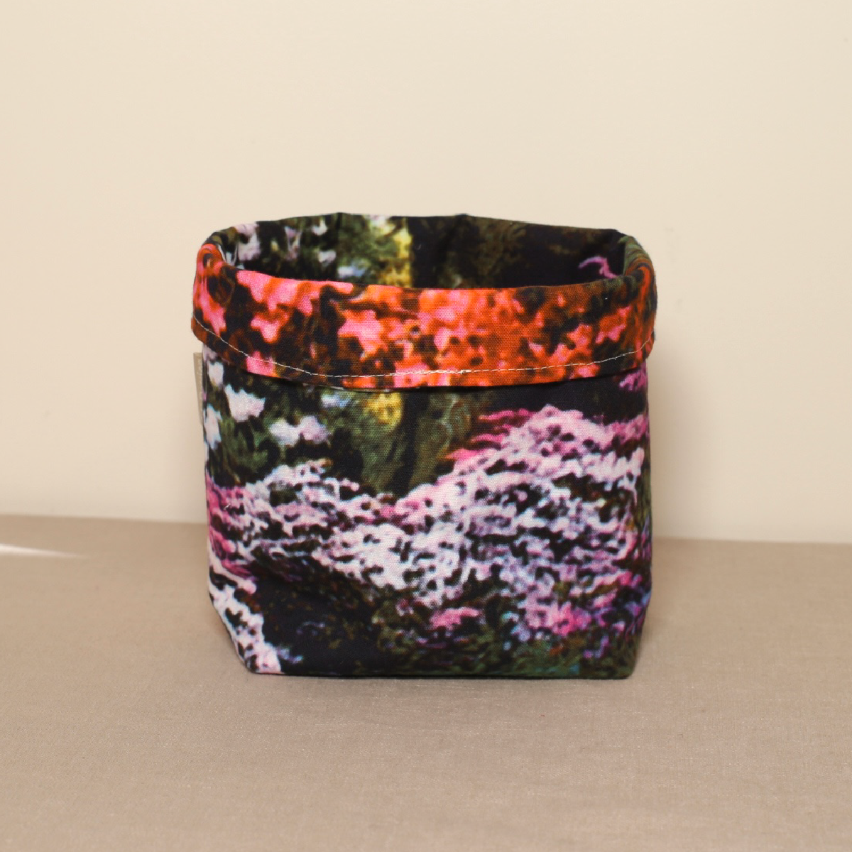 A multicolored fabric pot with a floral pattern, standing on a flat surface.