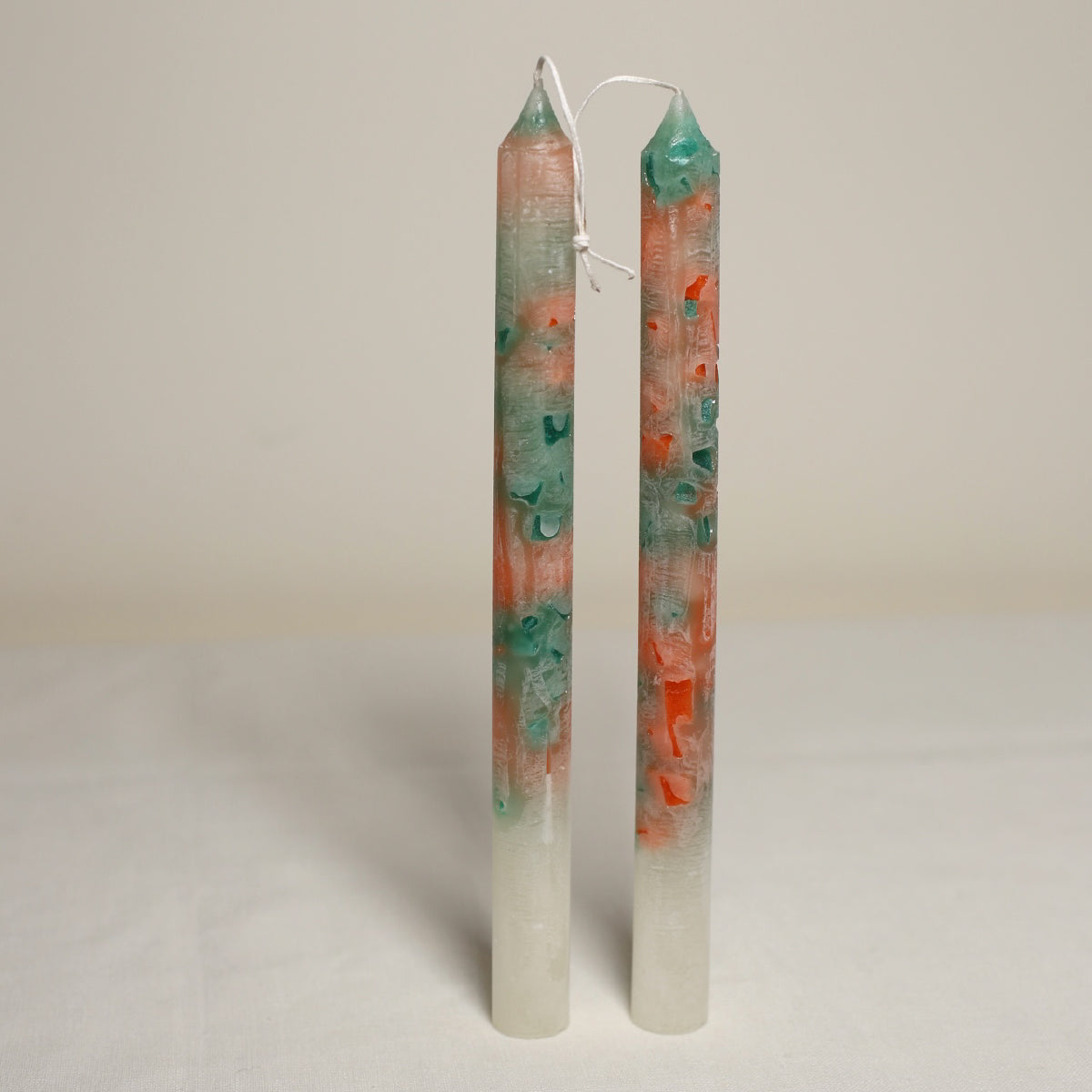A pair of marble effect table candles with white, green, and orange colors