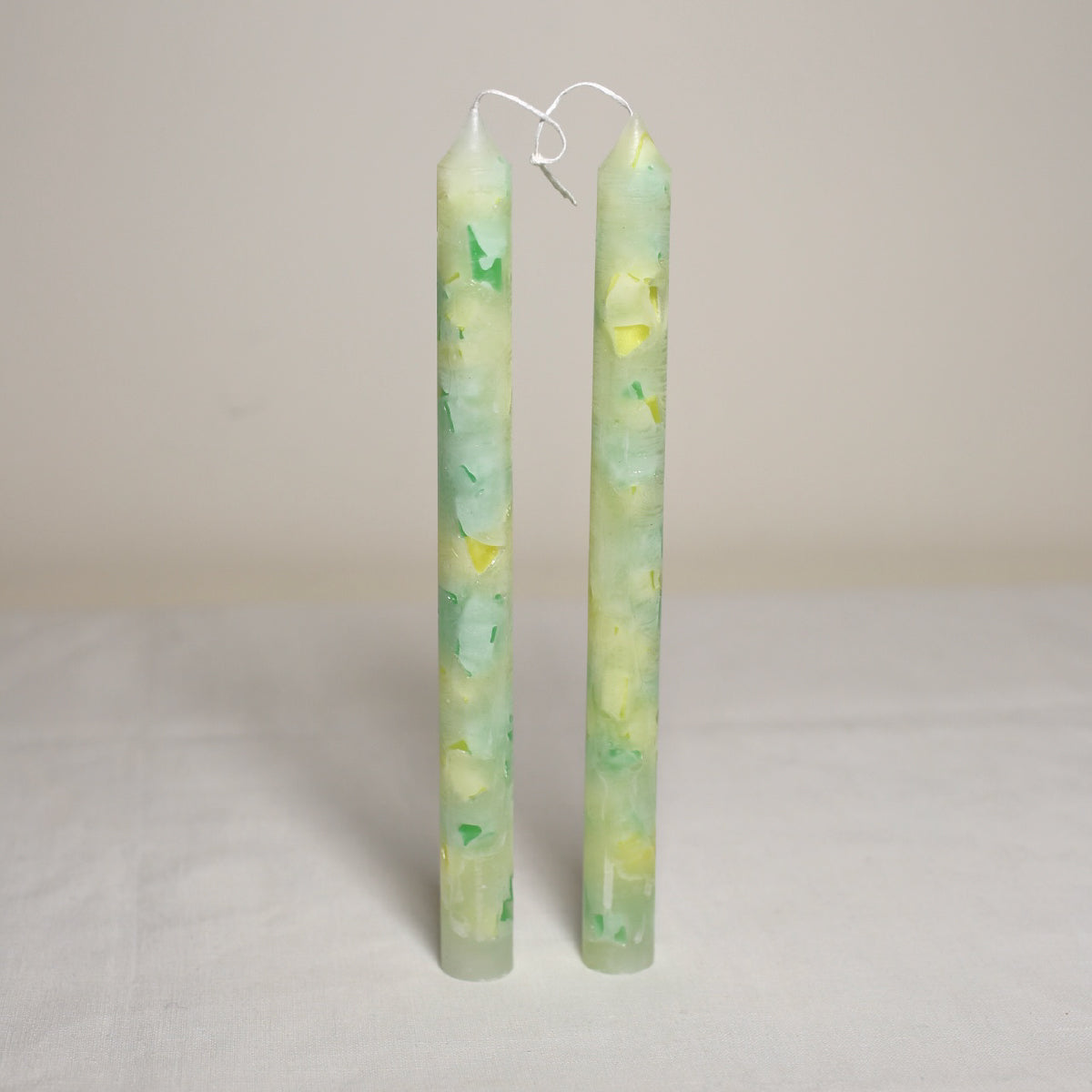 A pair of lime green marbled table candles placed vertically on a white surface.