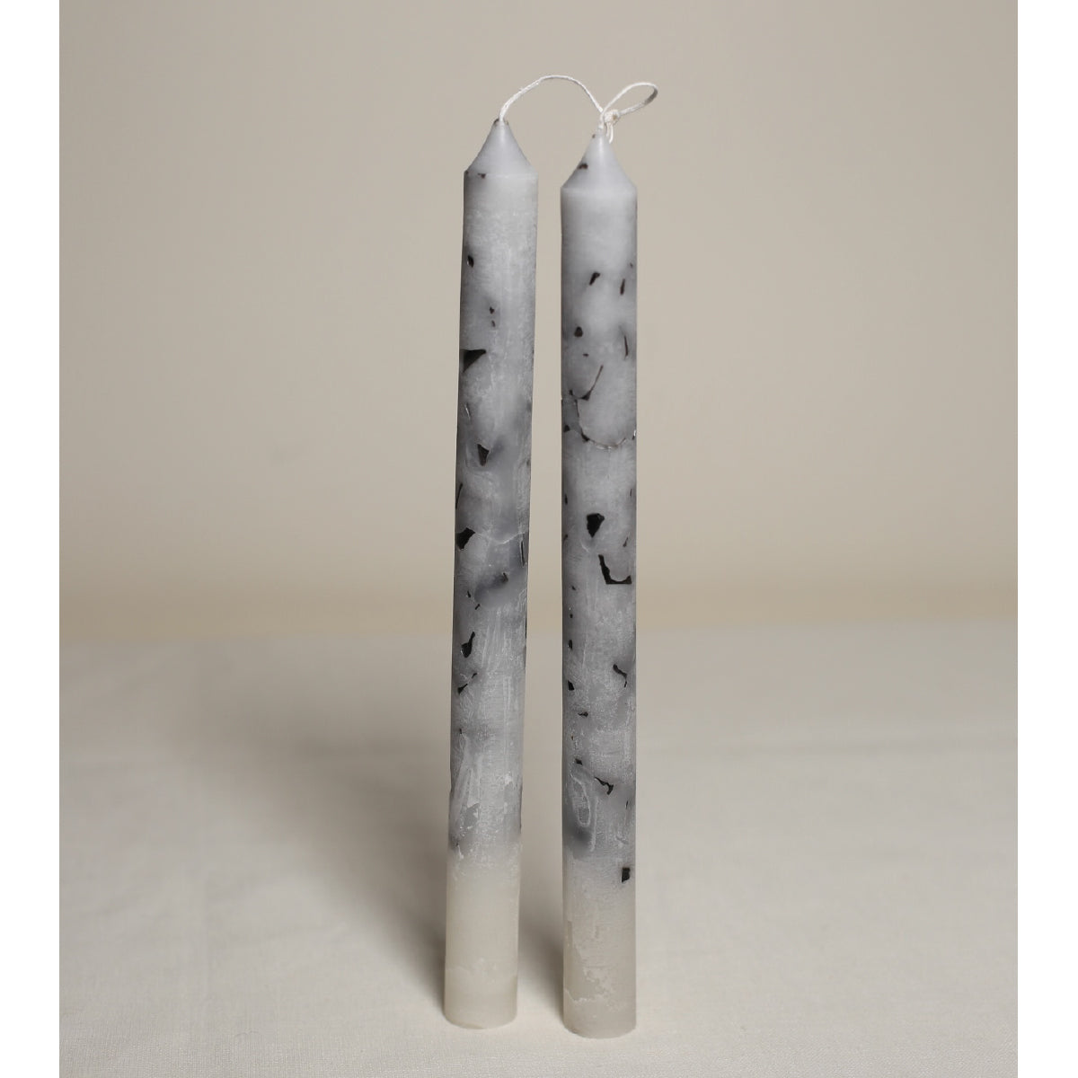 A pair of white marble effect table candles displayed upright on a light background.