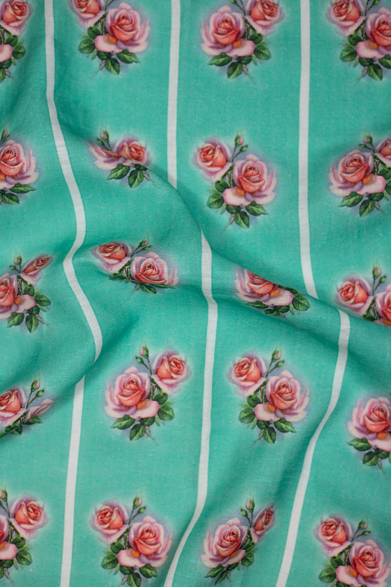 A vintage style green linen tea towel with a pink and green rose motif repeated vertically in four stripes down the tea towel.