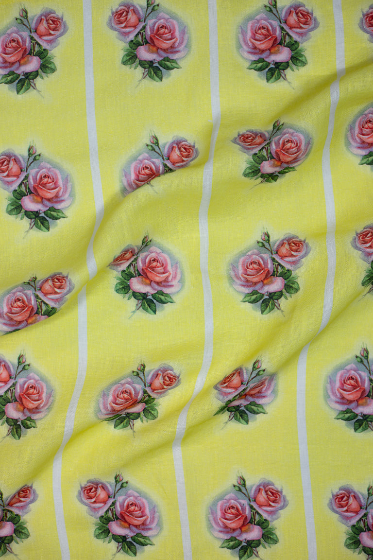 A vintage style yellow linen tea towel with a pink and green rose motif repeated vertically in four stripes down the tea towel.
