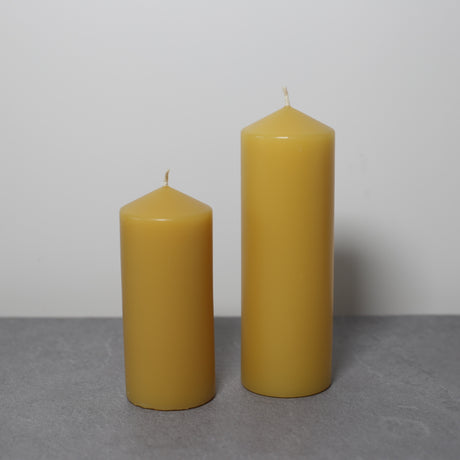 Beeswax pillar candles in two sizes on slate with white background