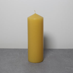 Beeswax pillar candle on slate with white background