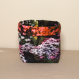 A multicolored fabric pot with a floral pattern, standing on a flat surface.