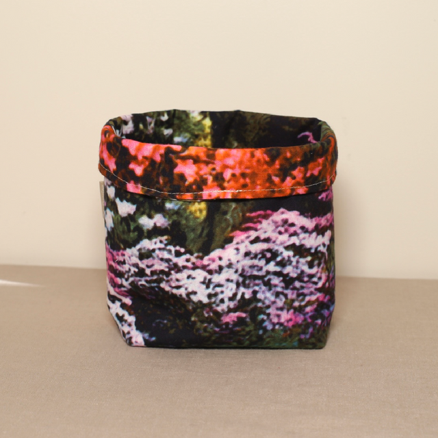 A multicolored fabric pot with a floral pattern, standing on a flat surface.