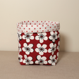 A red fabric pot with a floral pattern and a white polka dot rim on top.
