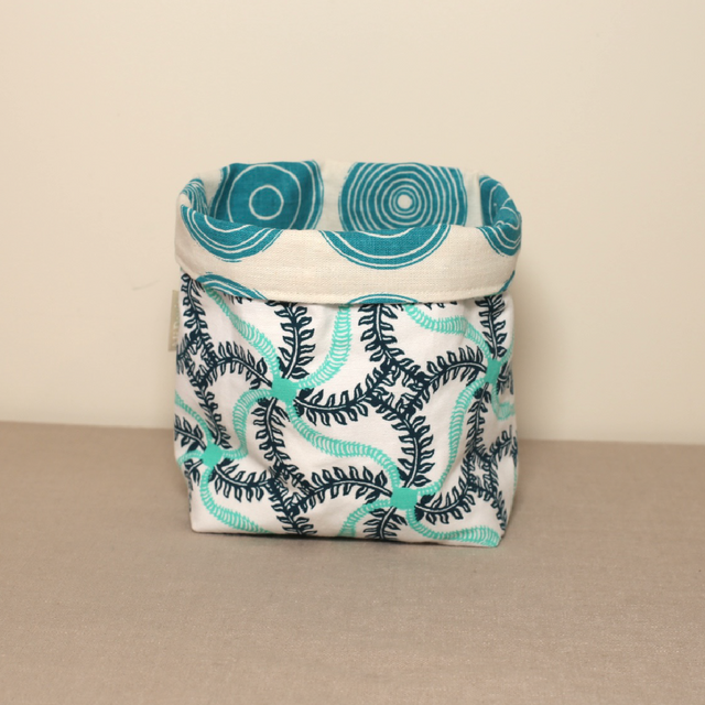 A fabric pot with a sea creature pattern in shades of blue and white, handmade from organic cotton.
