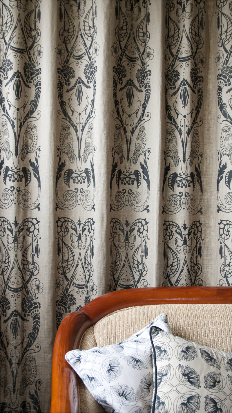 A hand printed curtain on european linen in a mid grey colour with a black art deco style flora and fauna print.