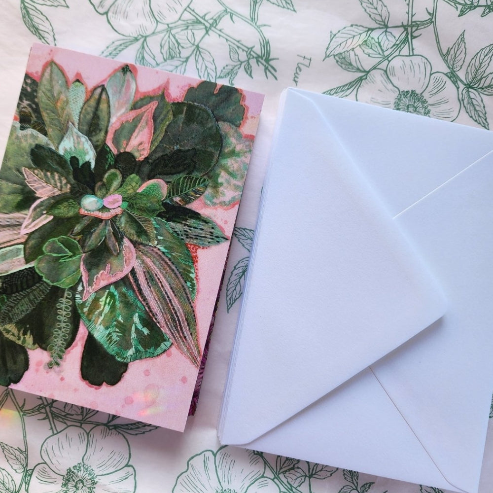 Green and pink floral card with embroidery art, laying next to envelope on patterned paper