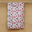 A pink flower printed hemp tea towel  handing next to a honey coloured concrete wall. 
