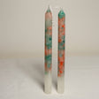 A pair of marble effect table candles with white, green, and orange colors