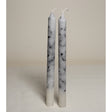 A pair of white marble effect table candles displayed upright on a light background.