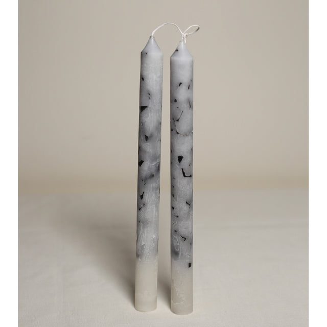 A pair of white marble effect table candles displayed upright on a light background.