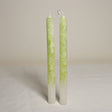 A pair of tall, marble effect, guava-colored table candles placed side by side on a light background.