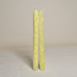 A pair of yellow marbled table candles placed upright on a surface with a light background.