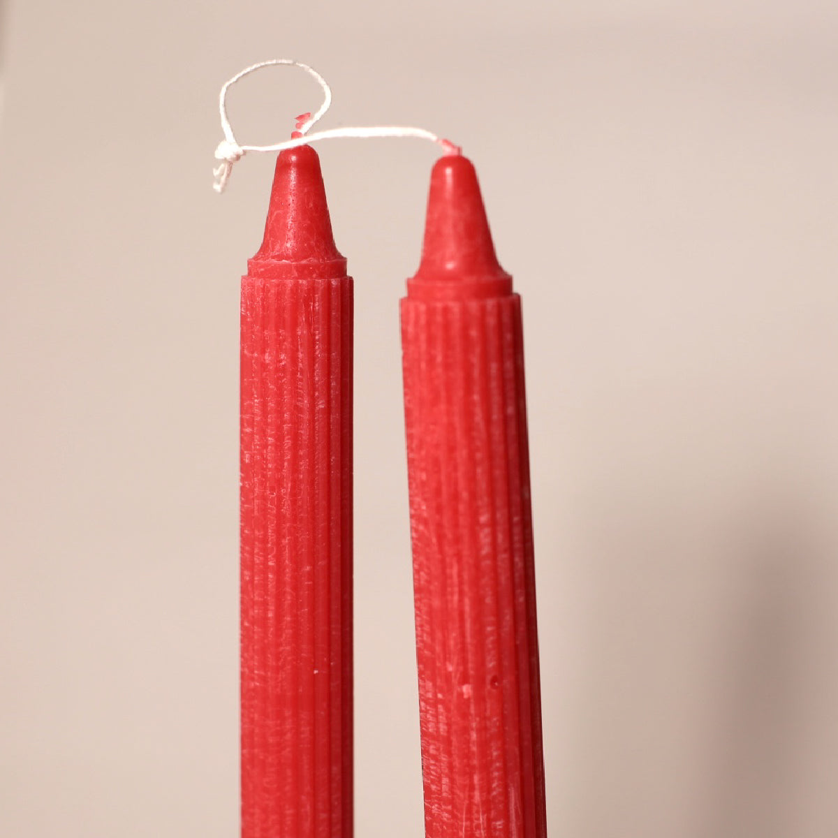 Two red candles with a textured surface on a beige background