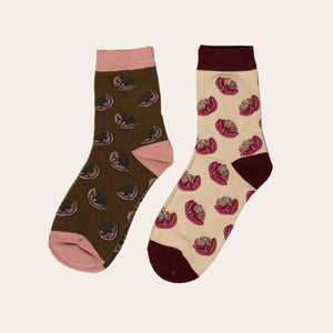Flatlay of two pairs of socks with pohutukawa flower on them sitting side by side. 