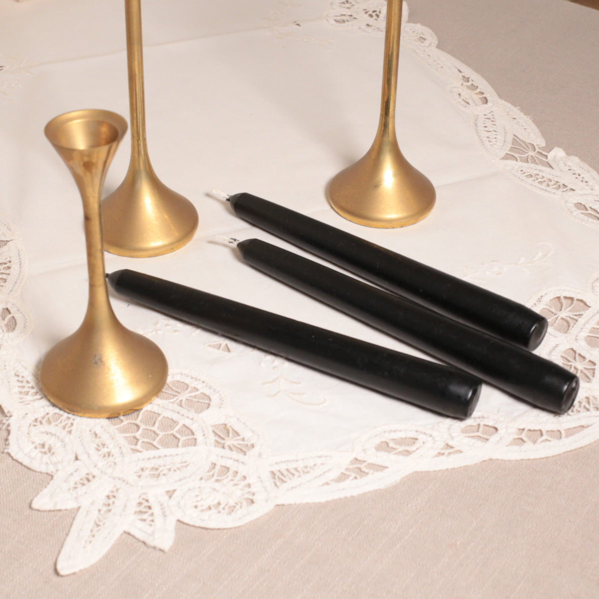 A pair of black tapered Venetian-style table candles on a lace doily.