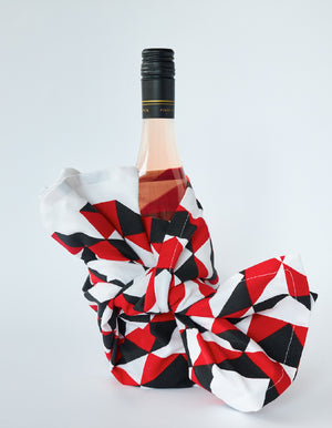 A wrapped wine bottle with a red, black and white geometric tea towel.